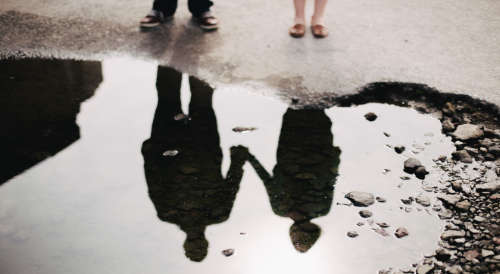 una pareja reflejada en un charco de agua