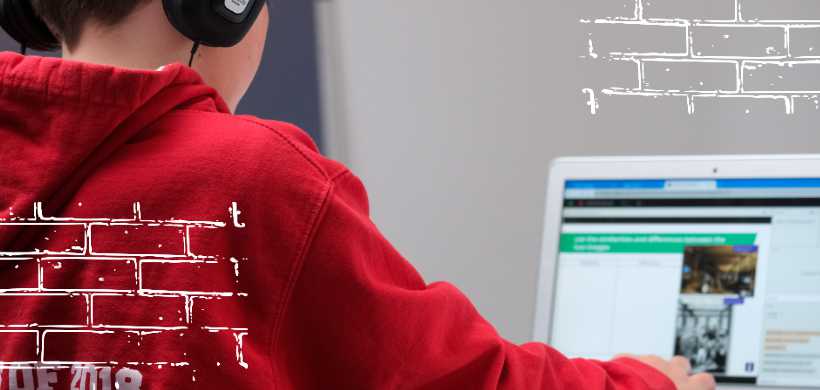 un niño con un hoodie rojo alfrente de una computadora