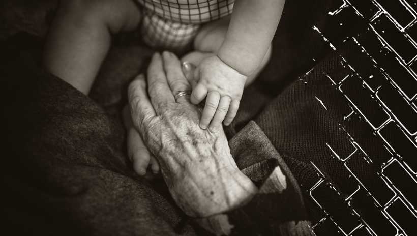 un hombre anciano aguantando la mano de un bebe