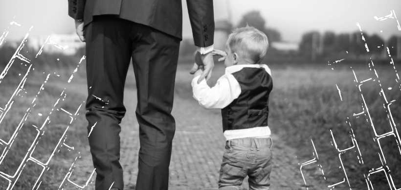 un padre, con un gaban, caminando y agauntando la mano de su hijo
