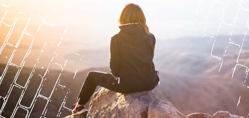 mujer sentada en una roca al lado de un risco, una vista de atardecer